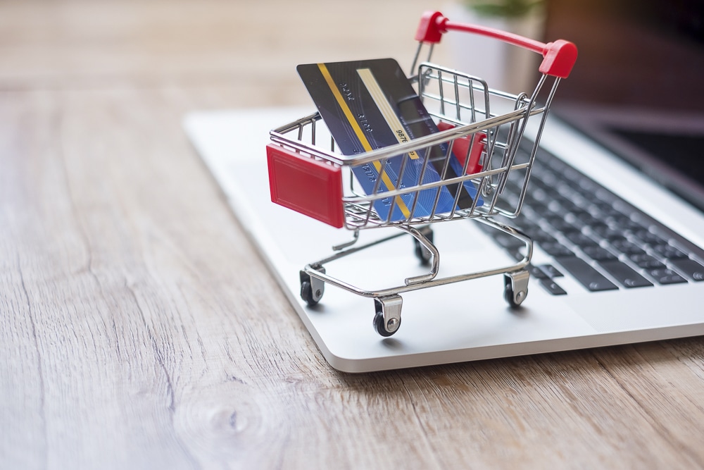 a mini shopping cart with a credit card on a laptop