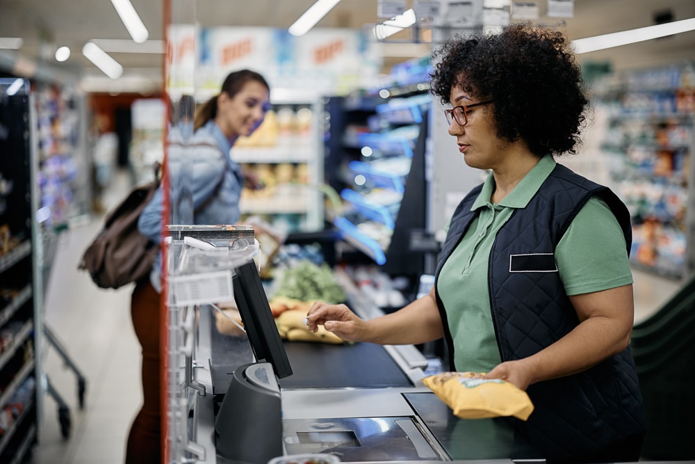 Supermarket cashier scanning customer's  groceries at checkout.